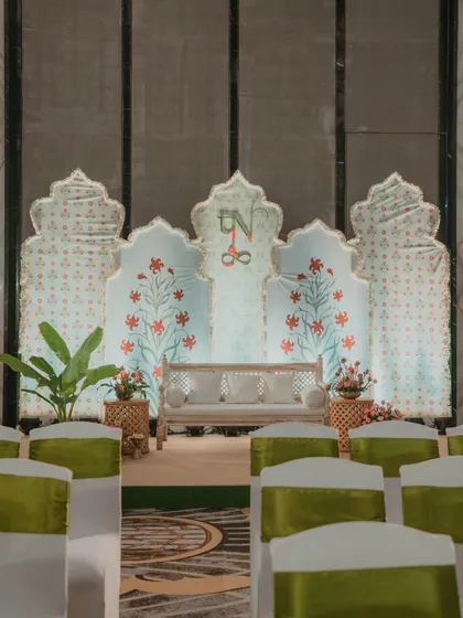 The stage for the Myra ceremony, featuring a backdrop of hand-painted floral motifs, creating a calm and artistic atmosphere.