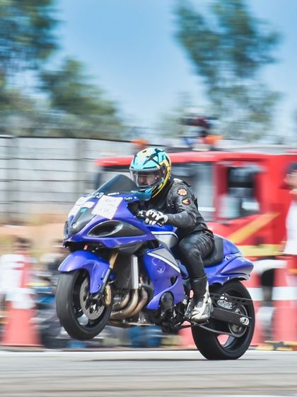 A modified Suzuki Hayabusa launches off the line, front wheel lifting in a power wheelie. This is the raw, untamed power of superbike drag racing.