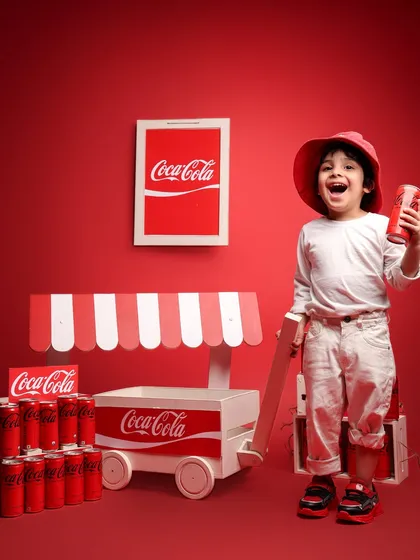 Holding a can of Coke, the young model for a day flashes a huge, happy smile. This image perfectly embodies the "Taste the Feeling" spirit in a kid-friendly way.