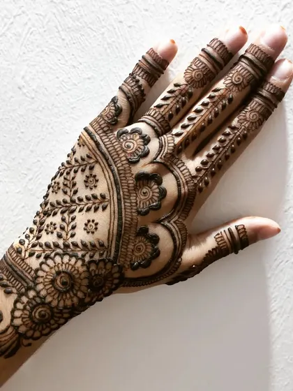 A beautiful party henna design with a mix of floral and leafy motifs. The pattern creates a lovely cuff and extends gracefully onto the hand.