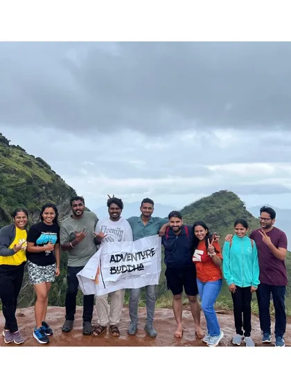 Our group at the top of a peak in Chikmagalur, with the Adventure Buddha banner held high against a backdrop of misty mountains.