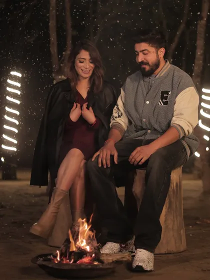 A cozy campfire scene from a pre-wedding shoot. The makeup is kept natural and fresh, ensuring it looks great in both the firelight and the cool night setting.
