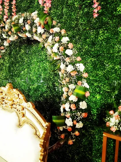 This image highlights a floral arch against a dense greenery wall. The mix of pink and white roses with baby's breath creates a soft, romantic feel, perfect for an engagement or baby shower stage.