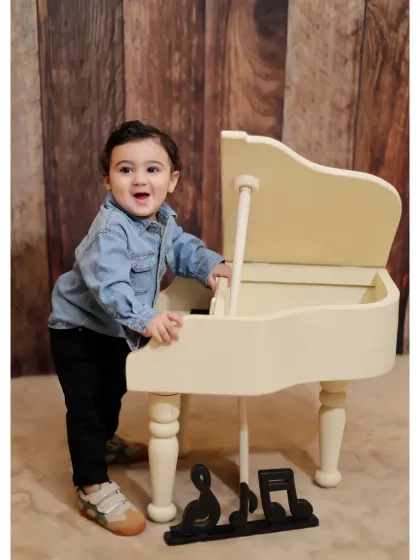 A happy toddler enjoying our miniature piano prop. We use interactive props to keep children engaged and capture their genuine curiosity and smiles.