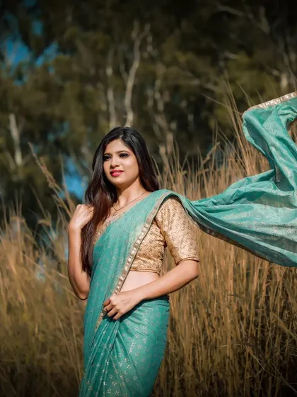 This image from a creative photoshoot shows a soft, natural makeup look that enhances features without feeling heavy. The flowing saree and outdoor setting create a dreamy, romantic feel, perfect for pre-wedding shoots or portfolio work.