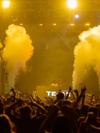 The crowd at IIM Indore with their hands up, surrounded by yellow-lit smoke. The energy is tangible.