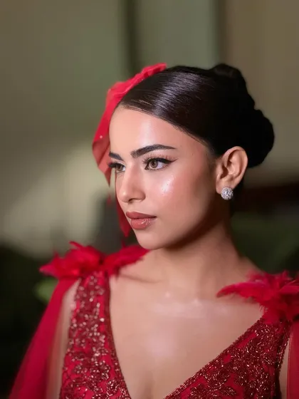A side profile showcasing the sleek high bun and the flawless, glowing skin. This look is all about sharp lines and high glamour.
