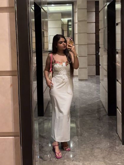 A full-length mirror selfie of the white dress, styled with a pop of pink from the bag and shoes.