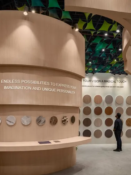 Inside the Safelam pavilion, product displays are integrated directly into the curved walls. This image shows a visitor interacting with the laminate samples, demonstrating how our designs encourage a tactile and personal experience with the brand's offerings.