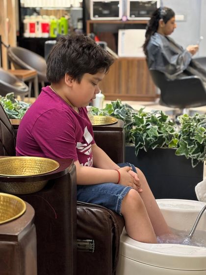 Even our youngest clients deserve some pampering. Here, a young boy is enjoying a relaxing foot soak as part of his comfortable salon experience.