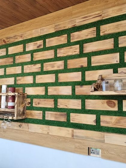 Another perspective of the wooden wall art, showing its scale and texture. The contrast between the warm, treated wood and the green artificial grass creates a striking visual effect.