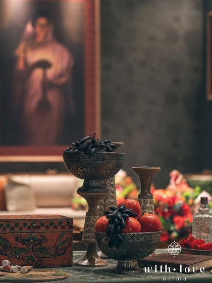 A tabletop arrangement featuring bowls of dark grapes and pomegranates, echoing the rich colors and still-life elements of Raja Ravi Varma's paintings.