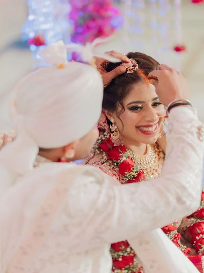 A close-up of the Sindoor ceremony, the bride's joyful smile as the groom applies the vermilion is the highlight.