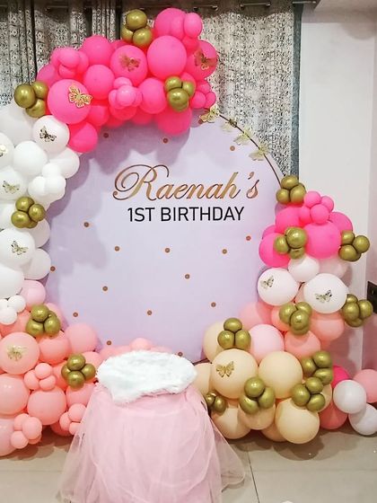 A beautiful butterfly-themed first birthday. This elegant setup uses a pastel color palette of pink, white, and gold, with a custom backdrop and delicate butterfly details on the balloon arch.