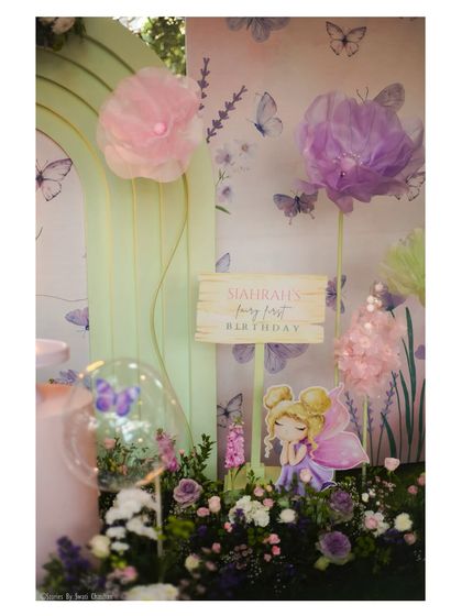 A close-up of the fairy theme details. This shot highlights the custom signage, a cute fairy cutout, and delicate paper flowers that contribute to the enchanting atmosphere.