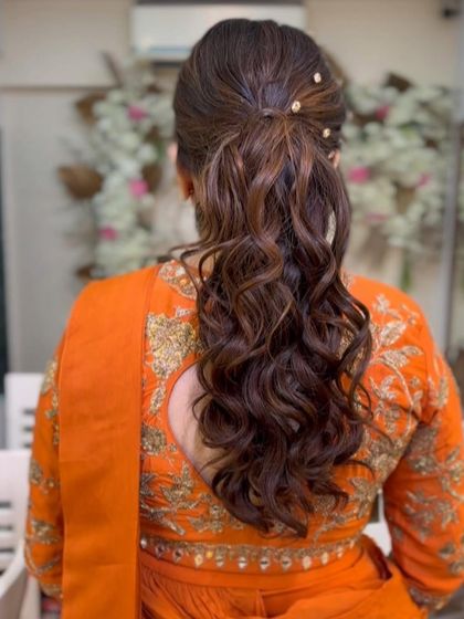 This messy ponytail with soft curls is accented with a few pearl pins for a touch of elegance. It's a beautiful and relaxed style for a pre-wedding event.