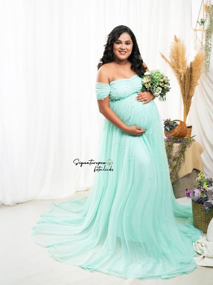 A soft and gentle portrait in the mint gown, with the mother holding a bouquet against a clean, bright background.