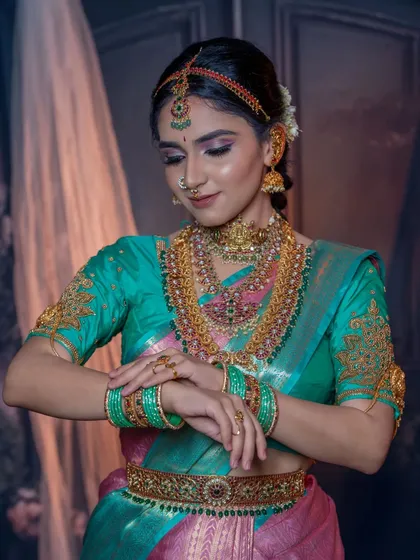 This pose highlights the embroidered blouse sleeves and the matching bangles. The makeup is cohesive with the entire color palette.