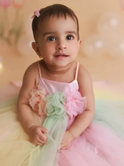 This sweet girl in her pastel rainbow dress is celebrating her first birthday. Close-up portraits like this capture the beautiful details and expressions of a one-year-old.