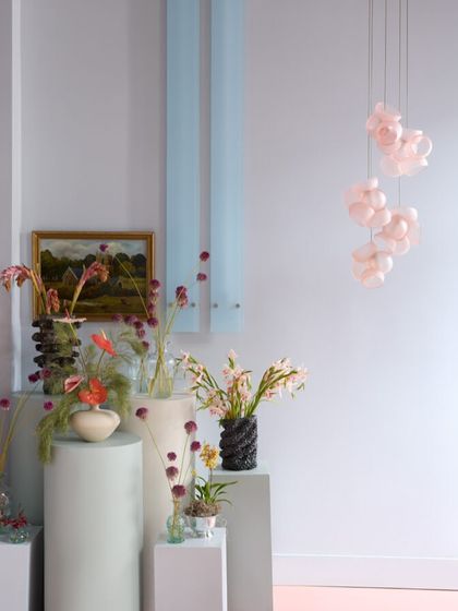 A small cluster of pink Bocci 100 pendants adds a touch of color and artistry to a room filled with floral arrangements.