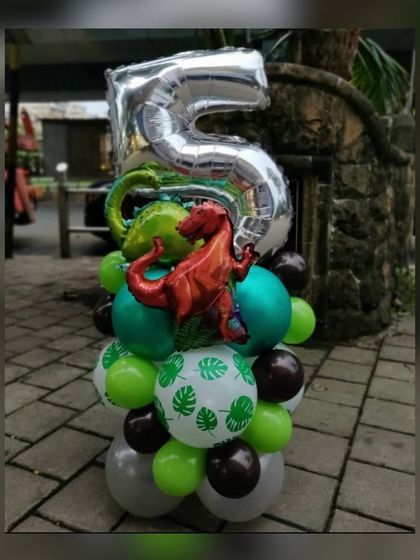 Another fun dinosaur balloon standee, this time for a 5th birthday. A large silver number "5" sits atop a base of green and brown balloons, complete with a red T-Rex foil balloon ready to party.