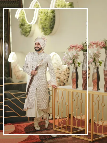 A full-length portrait of the groom in his elegant sherwani, posing confidently against a modern, well-lit interior.