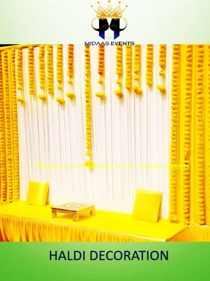 A simple yet elegant Haldi backdrop perfect for any space. This design uses a combination of white and yellow pleated drapes, with vertical strings of marigold flowers creating a classic and bright setting for the ceremony.