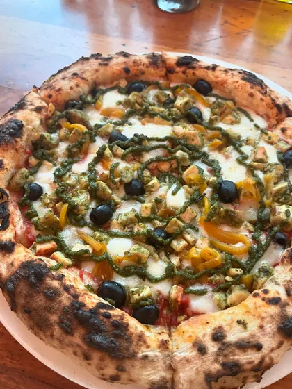 A delicious pesto chicken pizza, looking vibrant and ready to eat.