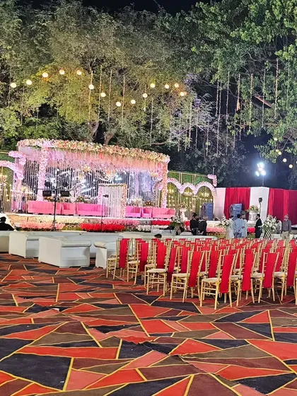 This wide-angle view shows the entire event space, demonstrating how a grand stage can anchor the layout of a large outdoor wedding. The guest seating is arranged to provide a clear view of the main event.