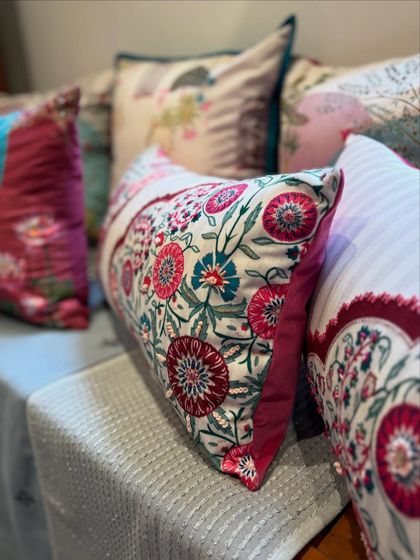 A collection of our vibrant floral and patterned cushions. The mix of bold pinks, deep reds, and intricate prints creates a rich, layered look that is full of personality and charm.