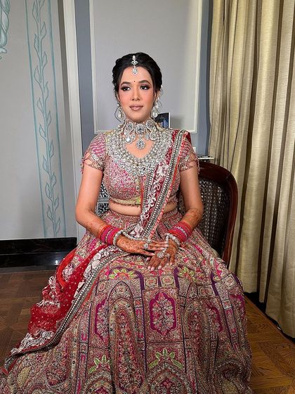 A full view of the bride ready for her ceremony. The floral bun complements her intricate Tarun Tahiliani lehenga and heavy jewelry, creating a cohesive and stunning bridal ensemble.