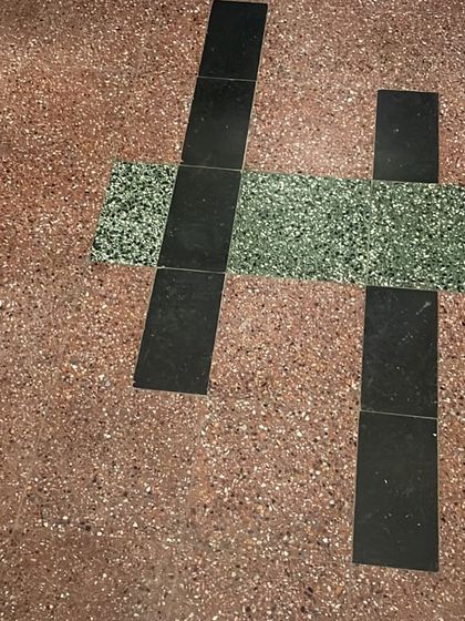 Testing new tile samples against the original terrazzo flooring, a part of our process to ensure new interventions are sympathetic to the original design.