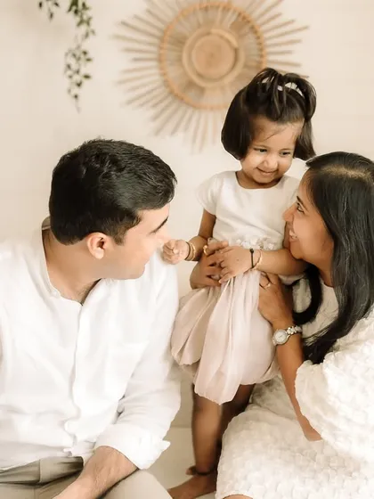 A playful moment between parents and their little girl.