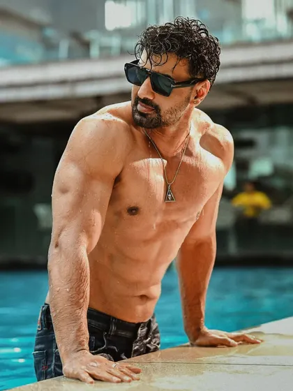 A sun-soaked, confident shot of Dev by the pool. His relaxed posture and sunglasses give off a cool, summer vibe, perfect for a lifestyle or fitness feature.
