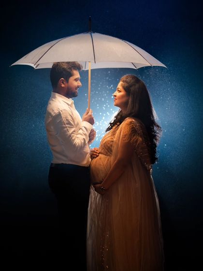 A classic and romantic couple's portrait under an umbrella, with a beautiful blue backlight creating a magical rain effect.