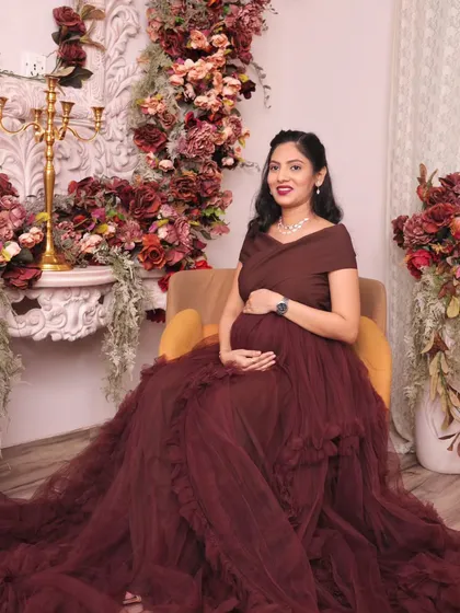 A serene seated portrait of the mom-to-be. The combination of the flowing gown and the rich floral decor creates a look of timeless elegance for her maternity album.