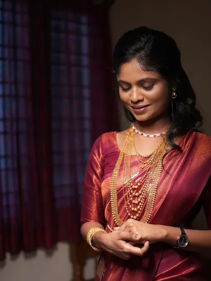 A beautiful reception look for Jemima, with a rich maroon saree and delicate gold jewelry.