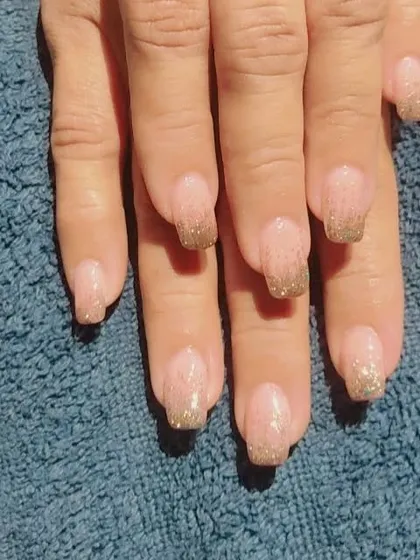 Another example of the gold glitter fade French manicure, showing how it looks on a different hand against a neutral background.