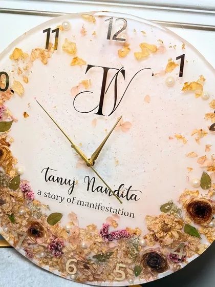Turn your wedding flowers into a timeless piece for your home. This 16-inch custom resin wall clock was made by preserving a couple's special varmala. I carefully arranged the dried flowers and personalized it with their initials and names, creating a functional piece of art that tells their story.