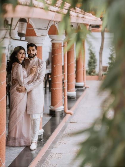 A full-length portrait of the couple in coordinated pastel outfits, framed by traditional architecture. This shot highlights their style and the beauty of the venue.