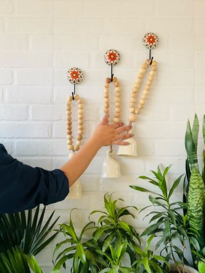 A close-up of someone adjusting our classic white boho beaded ceramic bells. The natural wooden beads and jute twine give these bells a rustic and bohemian feel, perfect for creating a calm and stylish atmosphere.