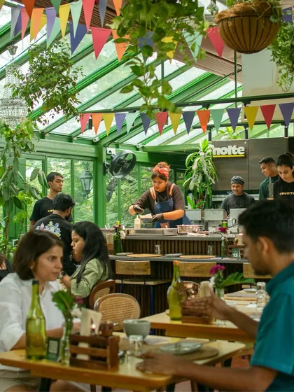 The vibrant, festive atmosphere of our Poee Sandwich Shop. The open kitchen allows guests to be part of the action, watching as chefs prepare their food.