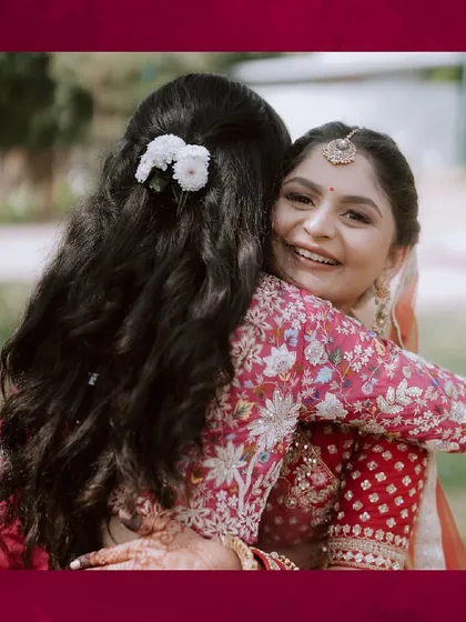 A warm hug between sisters. The bride's sister looks radiant with her soft makeup and simple floral hair accessory, perfectly complementing the bride's look.