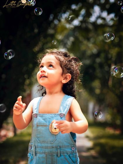 Chasing bubbles in the park. This candid shot captures the pure wonder and magic of childhood in a beautiful outdoor setting.