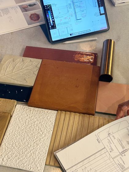 A client presentation in progress, with material samples, technical drawings, and digital sketches laid out. These meetings are highly collaborative, ensuring the design aligns with both aesthetic vision and practical needs.
