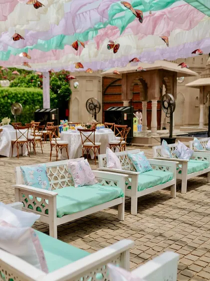 Comfortable and chic divan seating for guests, with pastel cushions that match the ruffled ceiling drapes and butterfly theme.