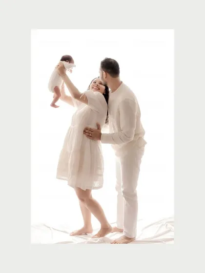 The same moment of celebration in soft color. The mother's happy expression as she lifts her newborn is the centerpiece of this image, showing the pure bliss of welcoming a new life into the family.