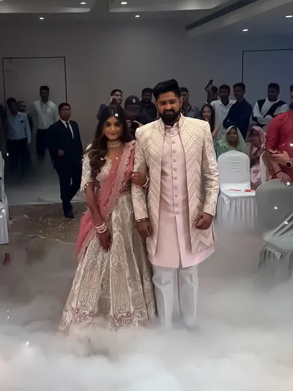 I love helping couples create cinematic moments like this. Here, the groom is wearing a light pink textured sherwani and the bride is in a complementary embroidered lehenga, making a grand entrance at their reception.