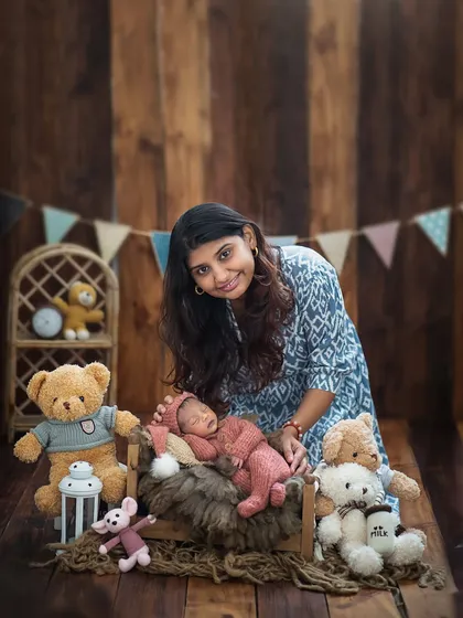 A loving mother gazes at her newborn, who is nestled among soft textures and cute teddy bears. This themed newborn session is full of warmth and sweetness.