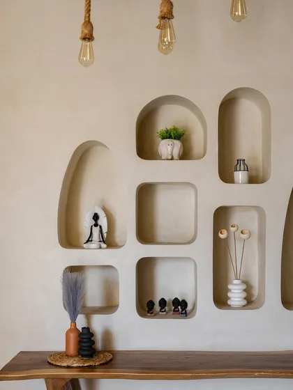 In the living area, we carved organic niches into the wall to create a unique display for art and accessories. This detail adds a soft, sculptural quality to the space, complementing the villa's natural aesthetic.
